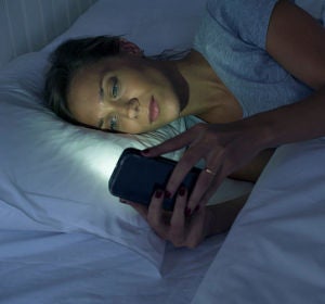 Una mujer mira el móvil antes de dormir Una mujer mira el móvil antes de dormir