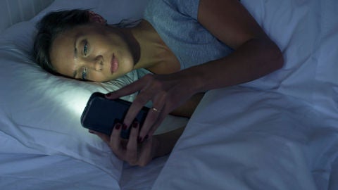 Una mujer mira el m&oacute;vil antes de dormir