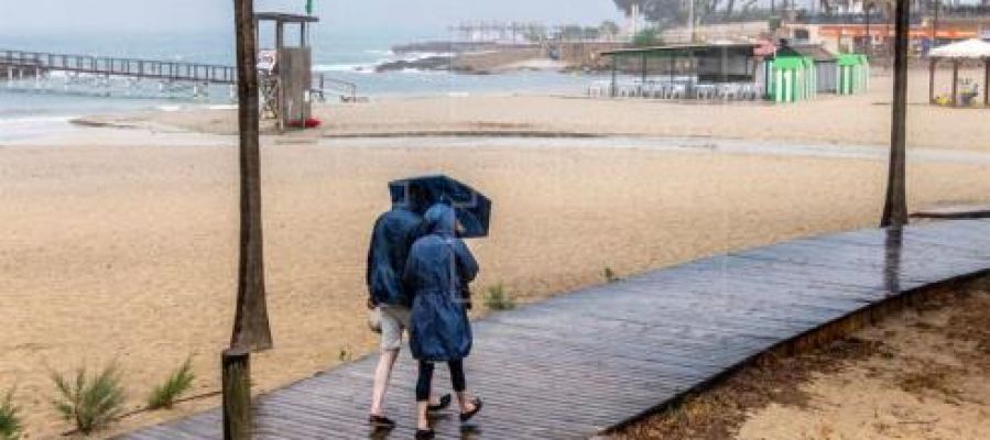 Dos personas se protegen de la lluvia, mientras pasean por la playa de Camp de Mar, en Mallorca. Dos personas se protegen de la lluvia, mientras pasean por la playa de Camp de Mar, en Mallorca.