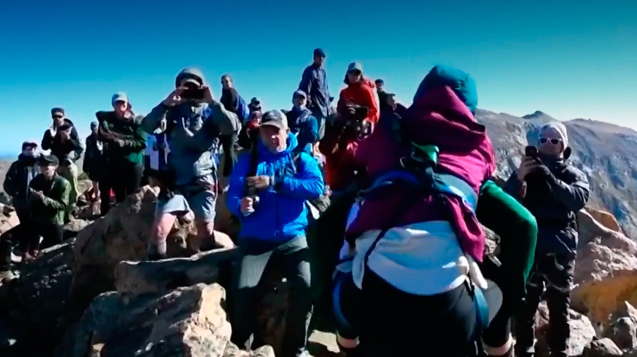 Unos montañeros ayudan a una mujer con discapacidad a alcanzar la cima de una montaña Unos montañeros ayudan a una mujer con discapacidad a alcanzar la cima de una montaña