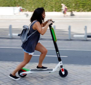 Una joven circulando en un patinete eléctrico Una joven circulando en un patinete eléctrico