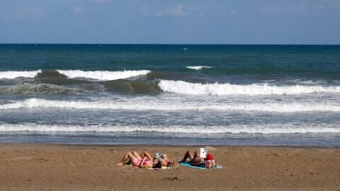 Tres personas toman el sol, el pasado mes de septiembre en la playa de la Malvarrosa de Valencia