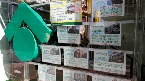Numerosos carteles de venta de pisos ocupan el escaparate de una entidad inmobiliaria Numerosos carteles de venta de pisos ocupan el escaparate de una entidad inmobiliaria