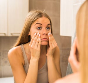 Mujer se mira el rostro en el espejo Mujer se mira el rostro en el espejo