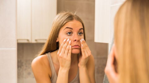 Mujer se mira el rostro en el espejo