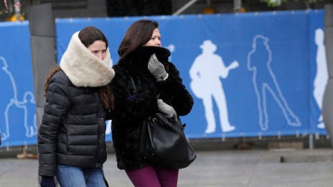 Dos personas se protegen del fr&iacute;o en una c&eacute;ntrica calle de Madrid
