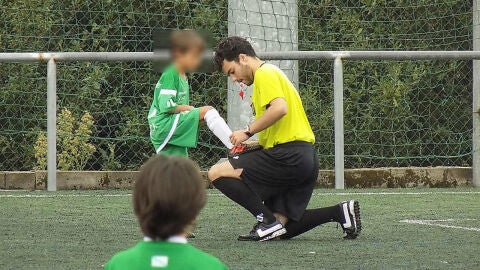 Un &aacute;rbitro le ata los cordones a un ni&ntilde;o