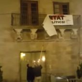 Dos personas descuelgan la pancarta por los políticos presos del balcón del Ayuntamiento de Cervera