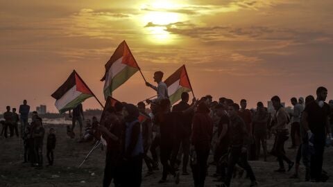 Varios palestinos ondean sus banderas durante enfrentamientos con soldados israel&iacute;es en la Franja de Gaza