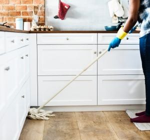 Una mujer friega el suelo de la cocina de su casa Una mujer friega el suelo de la cocina de su casa