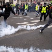 Varios "chalecos amarillos equivan botes de humo lanzados durante la protesta que hoy ha vuelto a recorrer las calles de París