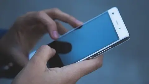 Imagen de archivo de una persona con un teléfono móvil en la mano Imagen de archivo de una persona con un teléfono móvil en la mano