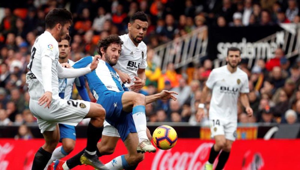 Los jugadores del Valencia, Sobrino y Coquelin, luchan el balón con el del Espanyol, Esteban Granero