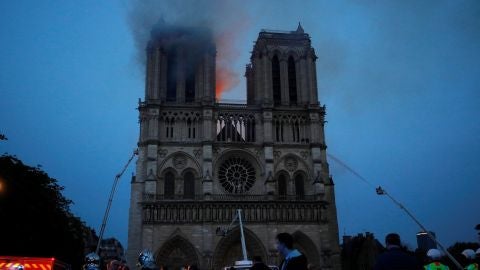 Los miembros de la brigada de bomberos de Par&iacute;s roc&iacute;an agua sobre la fachada de la catedral de Notre Dame