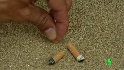 Cigarrillos en la arena de una playa. Cigarrillos en la arena de una playa.
