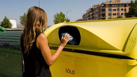 Una mujer deposita una botella de pl&aacute;stico en un contenedor amarillo.
