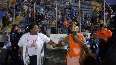  Aficionados ingresan al campo y se protegen de los gases lacrim&oacute;genos lanzados por las autoridades, debido a los disturbios a las afueras del Estadio Nacional por la cancelaci&oacute;n del cl&aacute;sico entre Olimpia y Motagua, en Tegucigalpa