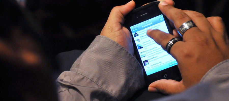 Un joven revisa su teléfono móvil Un joven revisa su teléfono móvil
