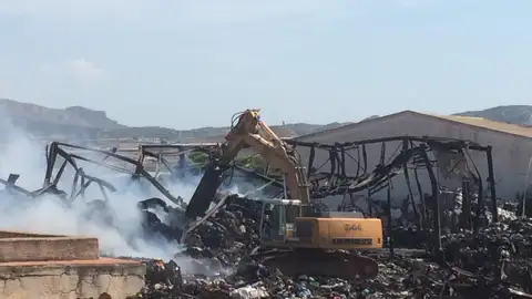 Un retroexcavadora en las labores de extinción del incendio en la nave de Aspe. Un retroexcavadora en las labores de extinción del incendio en la nave de Aspe.