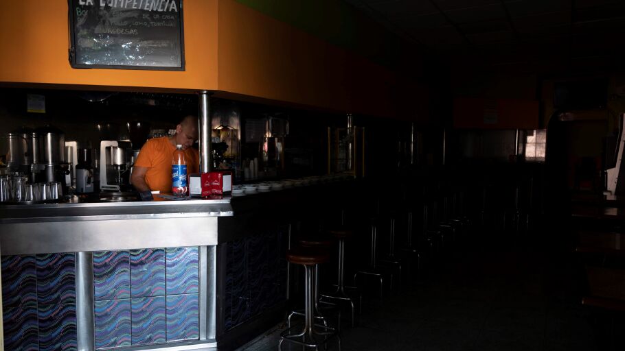 Un empleado de una cafeter&iacute;a de Santa Cruz de Tenerife intenta trabajar a oscuras mientras espera a que se restablezca el suministro el&eacute;ctrico la isla.