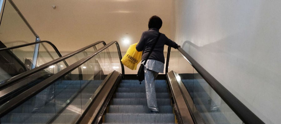 Una mujer sube en unas escaleras mecánicas Una mujer sube en unas escaleras mecánicas