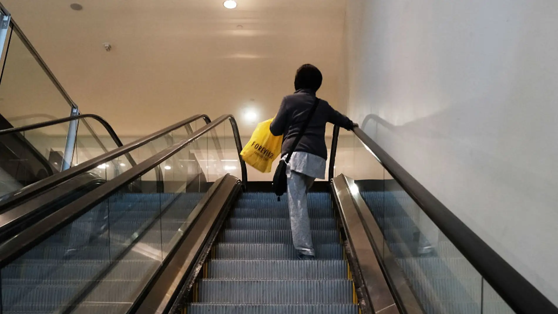 Una mujer sube en unas escaleras mecánicas