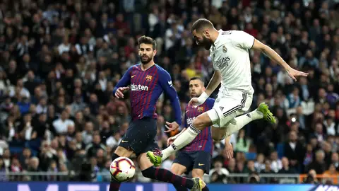 Benzema dispara a puerta ante la defensa de Piqué durante un Clásico Benzema dispara a puerta ante la defensa de Piqué durante un Clásico