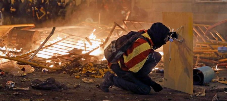 Un manifestante se protege con una plancha de madera durante los disturbios en Barcelona Un manifestante se protege con una plancha de madera durante los disturbios en Barcelona