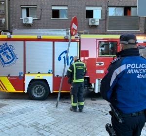 Un bombero y un policía tras el incendio declarado en Vallecas Un bombero y un policía tras el incendio declarado en Vallecas