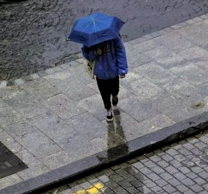 Una persona camina con un paraguas por la lluvia. Una persona camina con un paraguas por la lluvia.