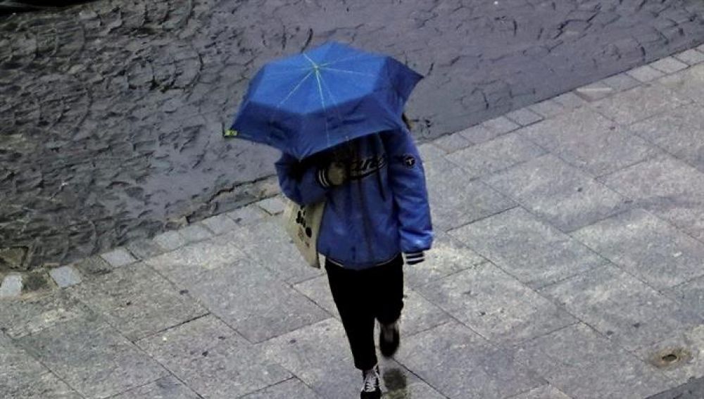 Una persona camina con un paraguas por la lluvia.