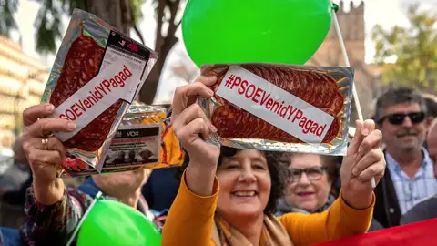 Vox concentra a decenas de personas ante la explanada del Parlamento andaluz en Sevilla, en un acto en el que se han repartido paquetes de chorizo en lonchas con la etiqueta #psoevenidypagad 