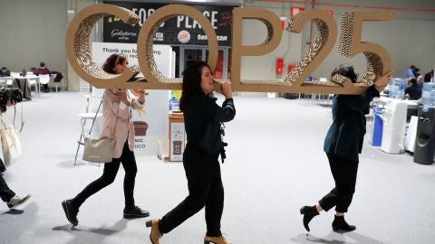 Tres mujeres retiran un logo del evento en el &uacute;ltimo d&iacute;a de la Cumbre del Clima