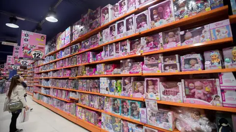 Una mujer mira una estantería llena de juguetes en una gran superficie Navidad