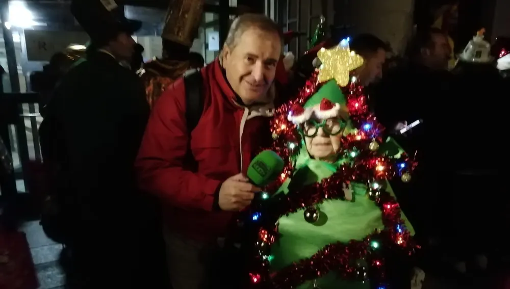 Carlos León junto al la mujer vestida de Árbol de Navidad que era la primera en la cola de entrada