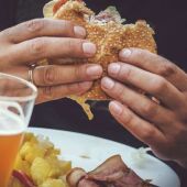 Imagen de archivo de un hombre comiendo una hamburguesa