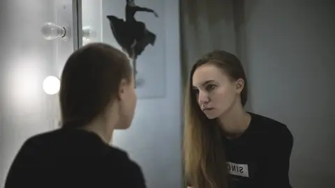 Una chica mirándose en el espejo de un baño Una chica mirándose en el espejo de un baño