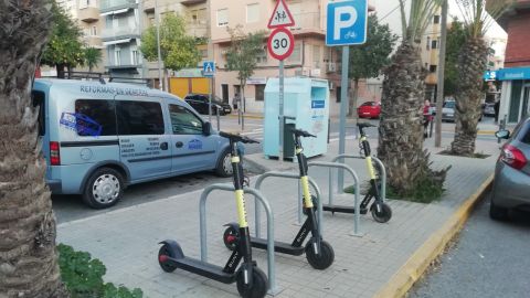 Patinetes de la empresa privada anclados a un aparcamiento de bicicletas en Elche.