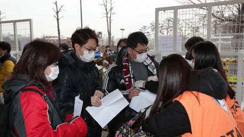 Aficionados entrando a un partido de f&uacute;tbol protegi&eacute;ndose del coronavirus