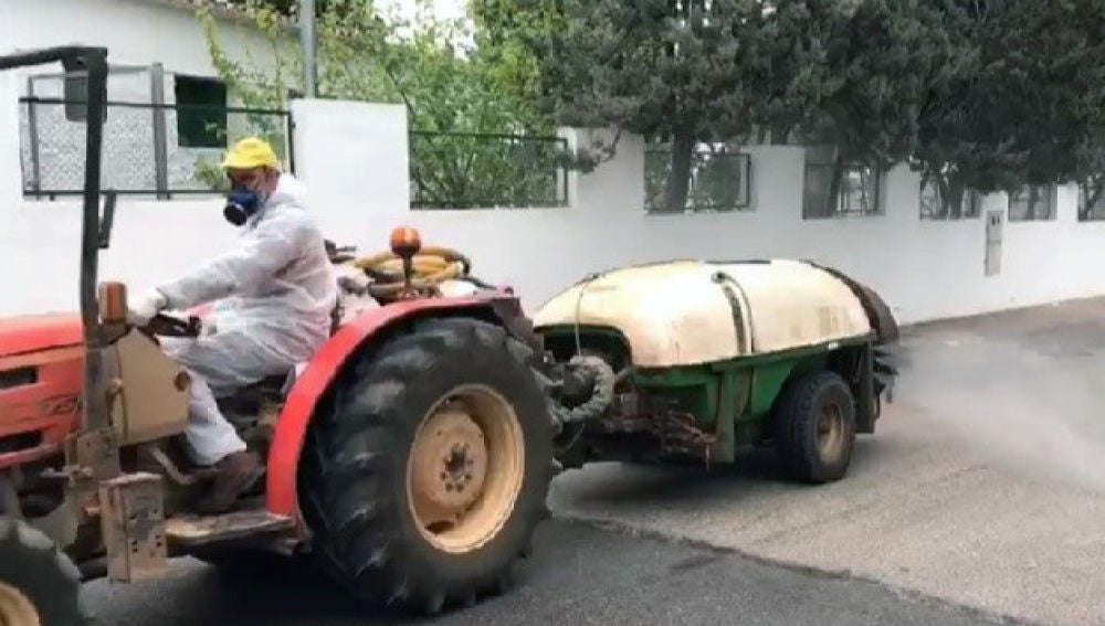 Tractor con cisterna y atomizador desinfectando las calles de una localidad.