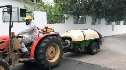 Tractor con cisterna y atomizador desinfectando las calles de una localidad. Tractor con cisterna y atomizador desinfectando las calles de una localidad.