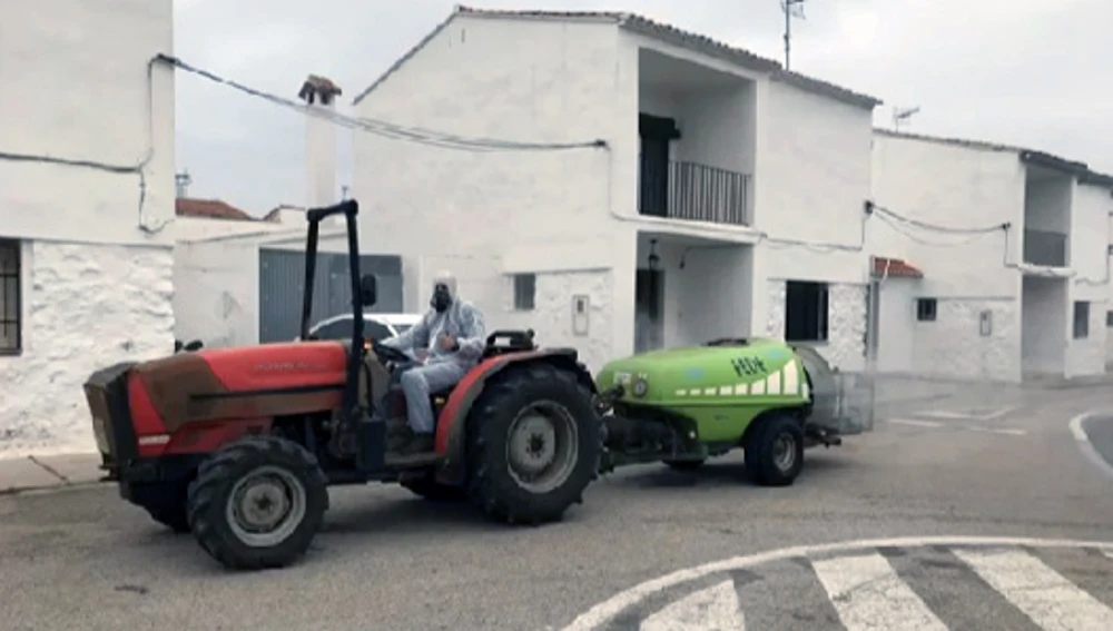 Tractor con cisterna y atomizador desinfectando las calles de una localidad.