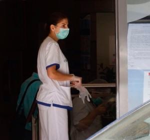Una mujer con una mascarilla entra en la residencia de mayores Una mujer con una mascarilla entra en la residencia de mayores