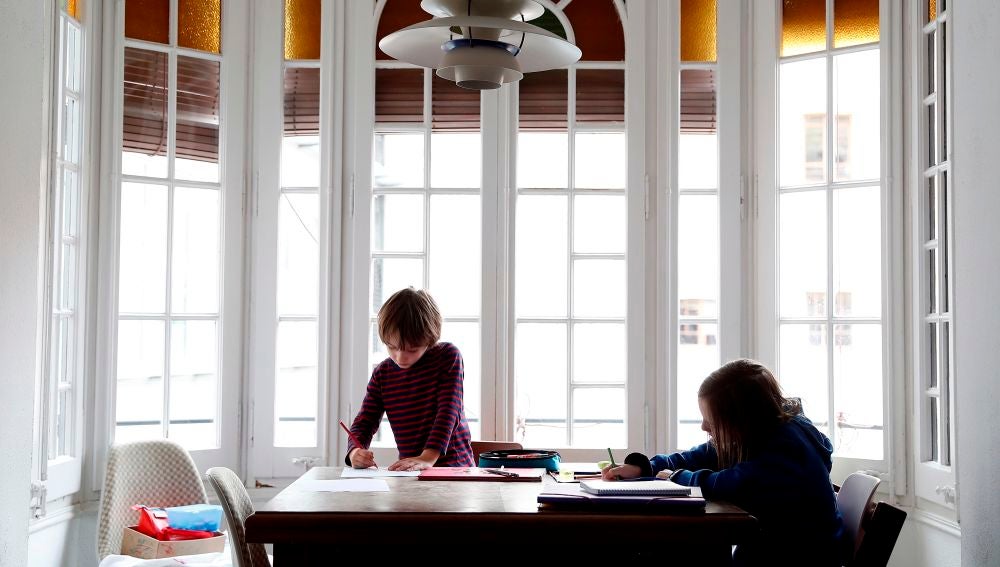 Dos niños hacen sus deberes en su casa