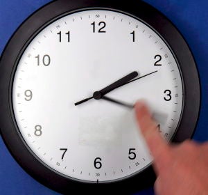 Una persona cambia la hora de un reloj Una persona cambia la hora de un reloj