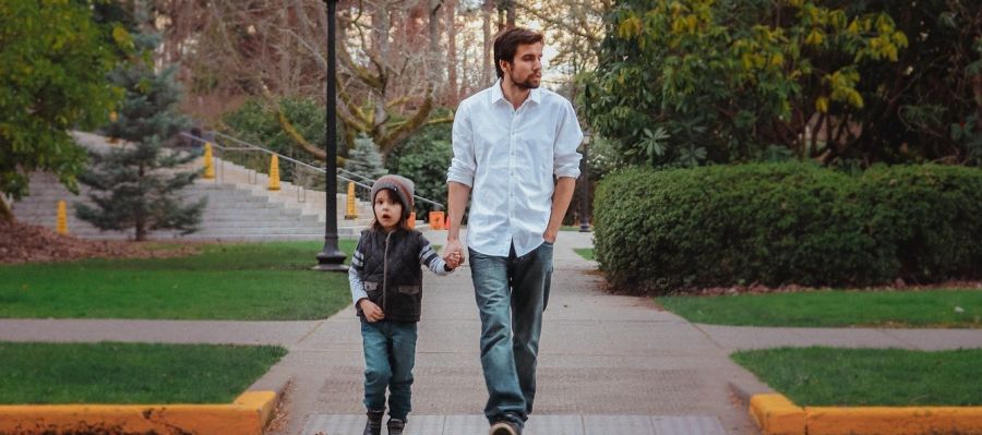 Un padre camina por la calle con su hijo Un padre camina por la calle con su hijo