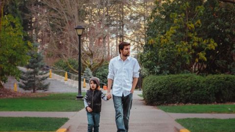 Un padre camina por la calle con su hijo