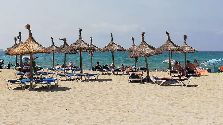 Turistas en hamacas bajo las sombrillas de la Playa. TURISMO