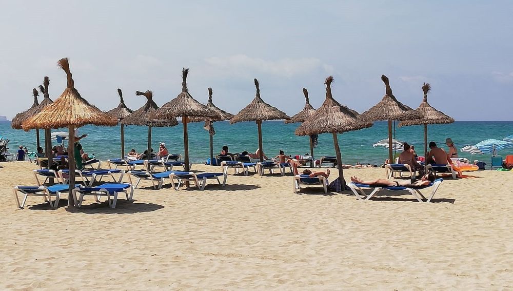 Turistas en hamacas bajo las sombrillas de la Playa.