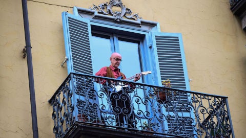 Un hombre toca la guitarra en su balc&oacute;n, en una ciudad italiana